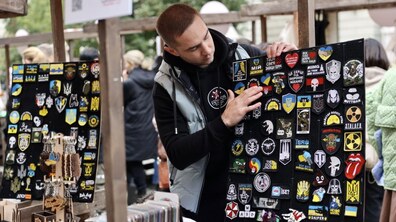 Чоловік показує шеврони на стенді