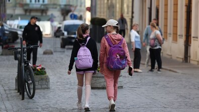 двоє школярок з наплічниками йдуть вулицею міста