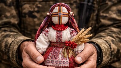 Ілюстративне фото. Чоловік у військовій формі тримає в руках ляльку-мотанку