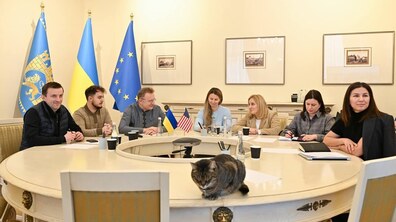 Мер Львова Андрій Садовий, депутатки та посадовці Львівської міської ради за круглим столом у Білій залі Львівської міської ради під час онлайн-зустрічі з представниками міста Тампа у США. Позаду прапори Львова, України та ЄС. На стінах картини міста. На столі два прапорці України та США. Спереду на столі сидить кіт Левчик