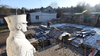 підготовчі роботи на місці зруйнованого музею Романа Шухевича. Зліва - статуя Романа Шухевича, а з правого боку працівник розбирає підлогу будівлі музею