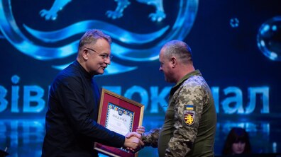 Міський голова Андрій Садовий тисне руку працівнику ЛМКП«Львівводокал», одягненому у військову форму, та вручає йому Подяку. Захід проходить у залі на тлі синьої екрана з логотипом Львівводоканалу.