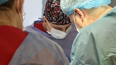 Троє лікарів у захисному одязі та масках під час проведення операції