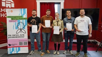На фото - п’ятеро представників молодіжних організацій, які взяли участь у реєструванні МолоФонду. Зліва на фото - банер, на якому написано: “Нелегко, але розвиваюся!”.