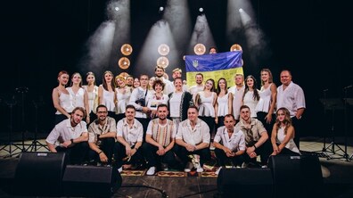 Колектив хору “Гомін” після одного із своїх виступів на сцені. Один із учасників тримає в руках прапор України