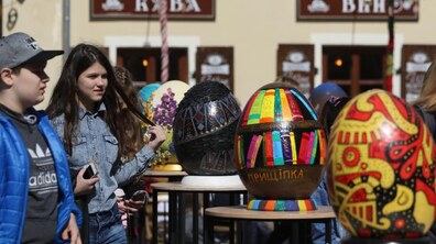 Дівчина та хлопець на виставці великих писанок на вулиці Львова. На другому плані видніється фасад будівлі. Фото ілюстративне.