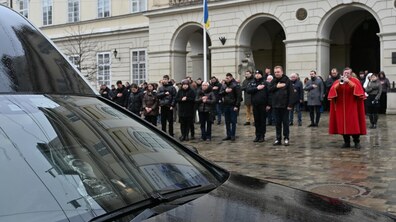 міська церемонія прощання з Вікторією Шпилькою. Мер Львова Андрій Садовий разом із рідними поліцейської слухають прощальну мелодію міського сурмача. На передньому плані автомобіль із фотографією Вікторії.
