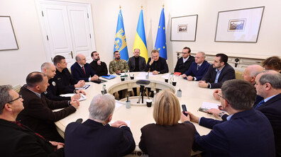 Ректори та представники міста сидять у просторій білій залі за круглим столом. Позаду них синьо-жовтий стяг, прапор ЄС та знамено міста