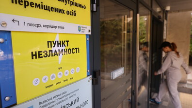 Жінка заходить у будівлю зі скляними дверима. На фасаді будівлі напис Пункт незламності