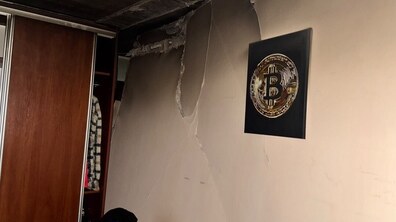 Пошкоджена після вибуху стіна. Від верхньої частини стіни відколовся значний фрагмент штукатурки та оздоблення, а по всій поверхні розходяться великі тріщини. Біля стіни стоїть шафа-купе, а на стіні висить декоративна картина.
