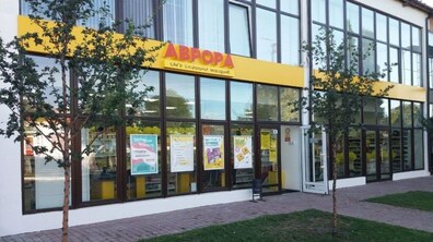 На фото магазин Аврора, розташований на першому поверсі будівлі офісного типу. На вікнах магазину рекламні банери