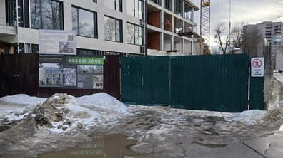 В’їзд на будівництво біля новобудови. Перед воротами — калюжі та мокрий бруд, який винесла техніка на проїжджу частину.