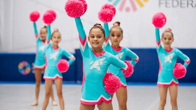 Юні черлідерки у яскравих блакитних костюмах з рожевими помпонами під час виступу.