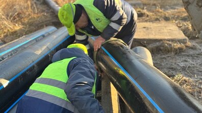 два працівники Львівводоканалу, одягнені у спецодяг, монтують новий водопровід із поліетиленових труб