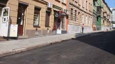 Вулиця Сембратовичів після ремонту — уздовж дороги простягається рівне темне асфальтове покриття без вибоїн чи тріщин. Зліва видно відремонтований тротуар.
