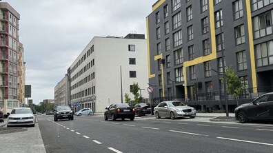 Відремонтована і відкрита для проїзду транспорту вул. Залізнична. Широка дорога з кількома автомобілями проходить між новими багатоповерховими будинками.