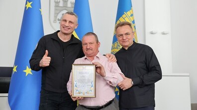 Мер Києва та Мер Львова із працівником одного із львівських комунальних підприємств під час нагородження у великій сесійній залі Ратуші, в руках якого подака від громади столиці
