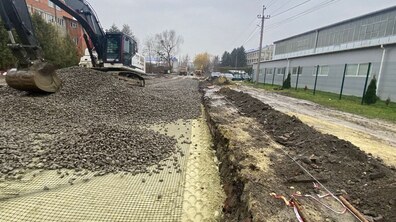 екскаватор розгортає щебінь для облаштування дорожньої основи на вул. Бескидській