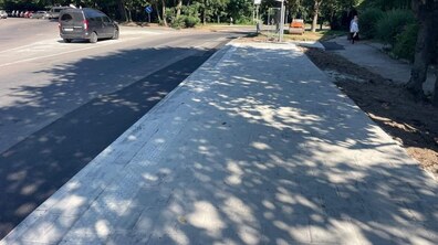 Вул. Франка неподалік кільця з вул. Козельницькою. На дальньому плані вулиця завертає праворуч убік зеленої насадженої зони, де видно скляну зупинку громадського транспорту.