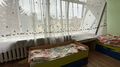 кімната в садочку № 70 на вул. Максимовича, 2 після обстрілу 5 жовтня – пошкоджене вікно, склом засипане дитяче ліжечко