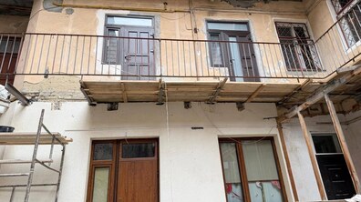 Процес ремонту балкону загального користування на другому поверсі будинку. Замість стаціонарної балконної плити тут встановлено дерев’яний настил з дощок. Він тримається на металевих швелерах (балках), що вмонтовані безпосередньо в стіну.