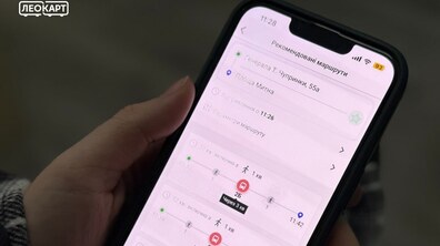 Людина тримає в руках смартфон із відкритим планувальником поїздок у застосунку LeoCard