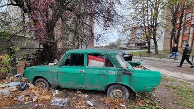 Стара покинута автівка зеленого кольору, без вікон, стоїть в одному із дворів Львова; всередині - покинуті речі та мотлох