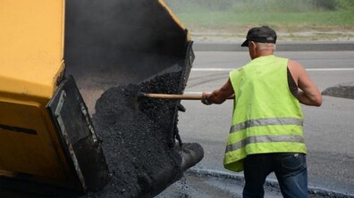 Працівник ремонтної служби вивантажує асфальт із спецтехніки