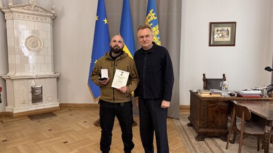 Міський голова Андрій Садовий та боєць Владислав Сосновський роблять спільне фото. Владислав тримає у руках відзнаку Головнокомандувача.