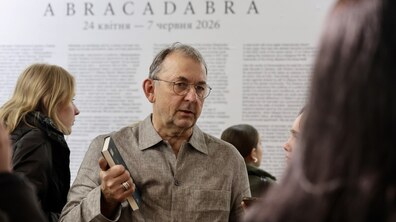 На фото автор виставки – Павло Маков. Позаду нього видніється назва виставки – «Abracadabra», а також текст про те, чому таке мистецтво важливе.