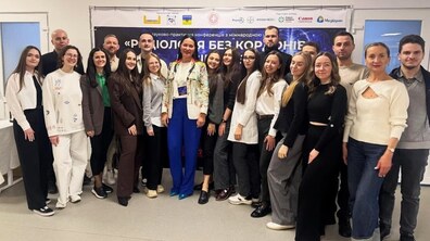 Спільне фото учасників конференції: велика група людей стоять разом у конференц-залі, позаду висить банер про конференцію «Радіологія без кордонів»