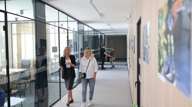 Дві жінки розмовляють, ідучи приміщенням Львівського центру надання послуг учасникам бойових дій на вул. Липинського, 11. Позаду також розмовляють двоє людей.