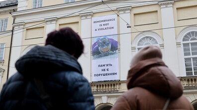 Жінки дивляться на банер із фото Владислава Гераскевича на фасаді Ратуші