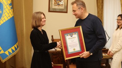 На фото мер Львова Андрій Садовий тисне руку та вручає подяку жінці