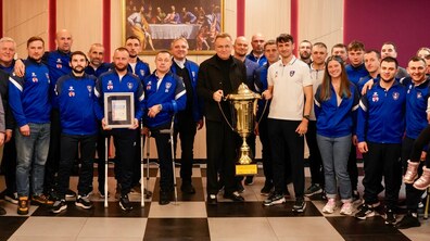 Учасники футбольного клубу “Покрова АМП” у спортивній формі фотографуються з міським головою Андрієм Садовим, який тримає у руках великий кубок.