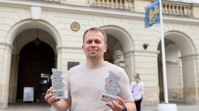 Юрій Теліпський стоїть на фоні Львівської міської ради та тримає в руках дві нагороди