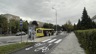 Велодоріжка на одній з вулиць Львова, поруч на зупинці громадського транспорту стоїть великий жовтий автобус