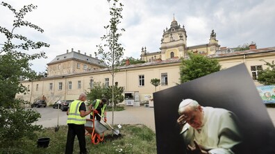 Процес висаджують дерева поблизу собору Святого Юра. На передньому плані розміщено світлину Папи Івана Павла ІІ.