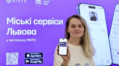 Заступниця з питань цифровізації Львівської міськради Олена Гунько презентує застосунок MISTO. Позаду неї — презентація. В руках вона тримає телефон із відкритим застосунком