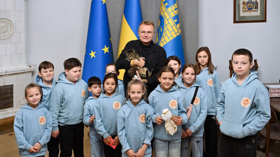 Учасники табору, одягнені у сині худі, роблять фото із міським головою Андрієм Садовим, який тримає на руках кота Левчика.