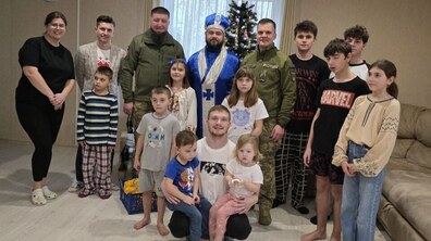 Спільне фото дітей, Миколая, батьків-вихователів та військовослужбовців, позаду – новорічна ялинка