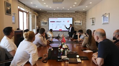 Учасники львівської делегації сидять за довгим столом та слухають презентацію представника стамбульського оператора IETT, що відповідає за автобусний транспорт. Спікер стоїть біля екрана з презентацією