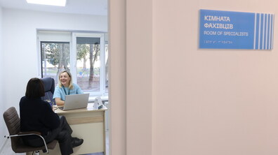 Працівниця Центру життєстійкості в окремій кімнаті консультує відвідувачку: обоє спілкуються, сидячи за столом; біля входу до кабінету табличка «Кімната фахівців»