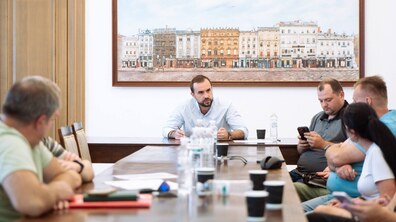У просторому і світлому кабінеті Львівської мерії сидить керуючий справами виконкому Євген Бойко. Зліва і справа за двогим столом сидять мешканці будинку – чоловіки і жінки. На столі пляшки з водою