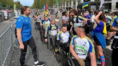 Львів’яни на кріслах колісних у формі з українською символікою готуються до забігу. Навколо - натовп