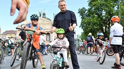 Мер міста Андрій Садовий позує для фото із маленькми велосипедистами. Позаду видніється Львівська національна опера