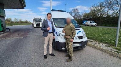 На фото начальник управління інвестицій та проєктів Львівської міської ради Андрій Павлів із військовим під час передачі авто. Позаду стоїть автомобіль швидкої допомоги