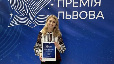 Ярина Кушнір, на церемонії “Освітня премія Львова”, у вишитому вбранні, фотографується на фоні банера та тримає у руках сертифікат.