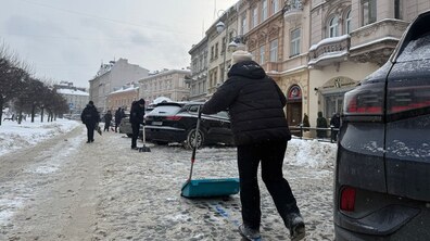 Люди вручну прибирають від снігу паркувальний майданчик