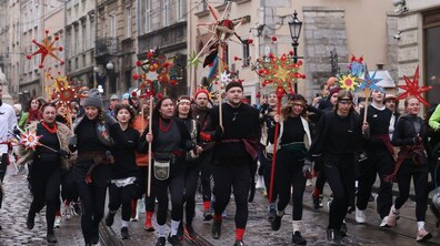 Кілька десятків учасників забігу зі звіздами в руках та одягнені з елементами українського строю біжать площею Ринок